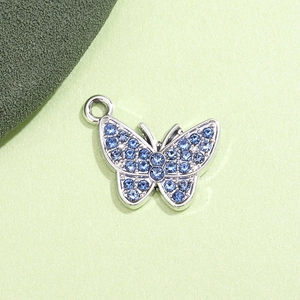 Dettaglio di un ciondolo a farfalla in argento con strass blu per gioielli fai da te