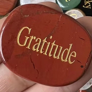 Polished natural oval stone with gold engraved Gratitude text held in hand