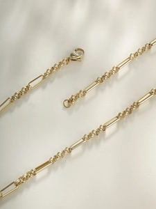 Close-up of gold chain featuring a paperclip and round link pattern with lobster clasp