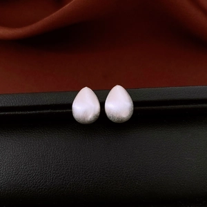 Detail of teardrop earrings with matte gradient finish from white to silver on a display