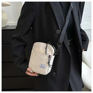 Detail of off-white nylon crossbody bag with 'HELLO WEEKEND' tag and adjustable strap