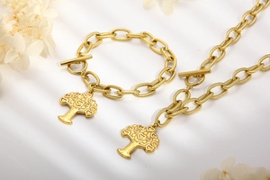 Detail of chunky gold chain jewelry set featuring heart tree of life pendants and T-bar toggle