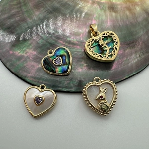 Detail of 18K gold-plated heart pendants featuring black and white shell with rabbit motifs