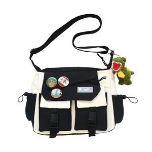 Japanese style black and white canvas messenger bag with dinosaur plush charm and badges