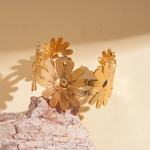 Vue détaillée du bracelet jonc doré en forme de marguerite sur une pierre naturelle