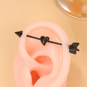 Close-up of black heart arrow industrial barbell piercing on silicone ear model
