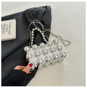 Close-up of silver bubble acrylic clutch with pearl chain and metallic strap