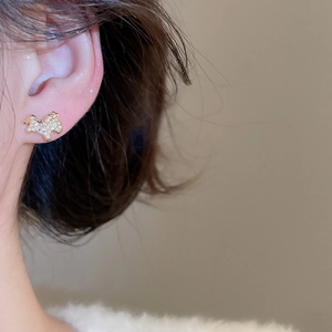 Détail d'une boucle d'oreille chiot en or avec incrustation de zircon sur l'oreille