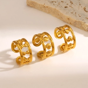 Three gold stainless steel rings with bow, shell, and heart designs on a minimalist stone