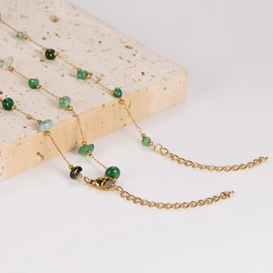 Elegant gold necklace with vintage green emerald stones on a natural stone base