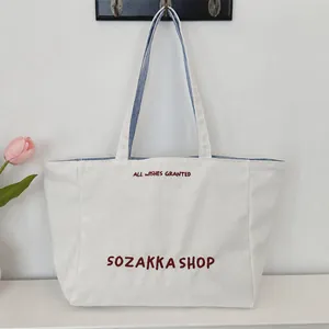 Detail der roten Bestickung auf weißer Canvas-Tasche mit gestreiftem Innenfutter