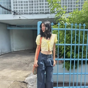 Haut court jaune à nouer pour femme assorti à un jean bleu foncé à jambes larges