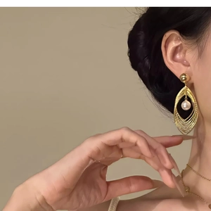 Detail view of multi-layer hollow teardrop earrings with a white pearl on a model