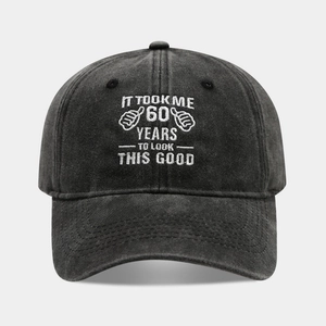 Detailed close-up of white 60th birthday embroidery on washed black cotton baseball cap