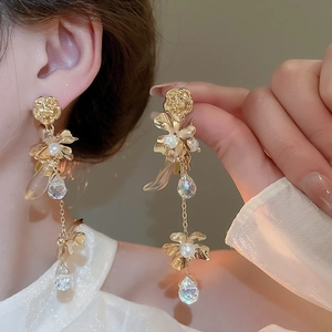 Detailed view of long gold floral tassel earrings with white pearls and faceted pendants