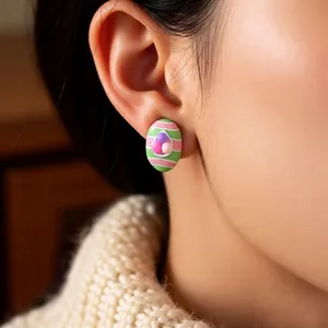 Easter egg stud earrings with colorful stripes and beaded details on a female model