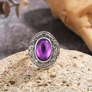 Macro shot of vintage silver ring with large oval purple gemstone on rustic rock