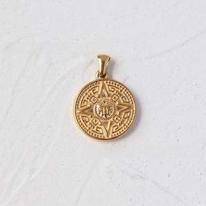 Detailed close-up of 18K gold plated coin pendant with Mayan sun relief patterns