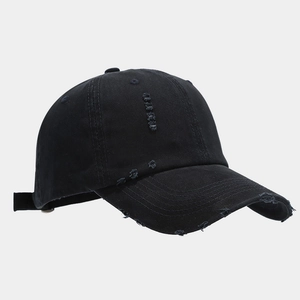 Detail view of the distressed edges and vintage worn holes on black cotton baseball cap