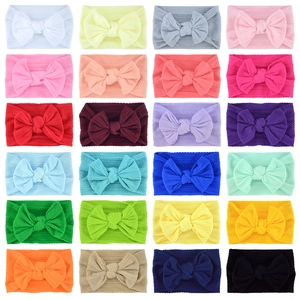 Collection of 24 colorful knitted nylon bow headbands for babies in a grid layout