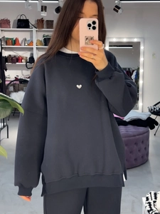 Détail d'un sweat-shirt gris foncé ample avec broderie cœur et pantalon en tricot