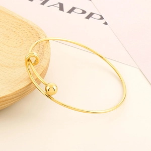 Detail view of gold minimalist stretch bead bracelet with spherical ends on wood