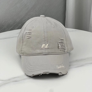 Close-up of distressed light gray baseball cap with 'N' embroidery on marble surface