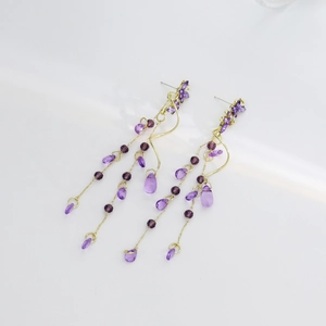 Close-up of purple petal flower drop earrings with golden chains and faceted beads