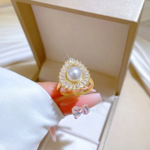 Detailed macro of a gold pear-shaped ring with a white pearl and radiating crystals