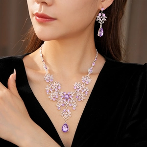 Close-up of vintage floral necklace and earrings set with purple rhinestones on model