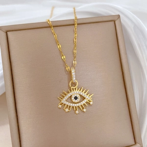 Macro shot of gold evil eye pendant with clear zircons on beige jewelry box display