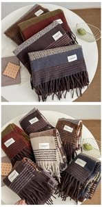 Folded colorful scarves with fringe detail and fashion tags on a minimalist background