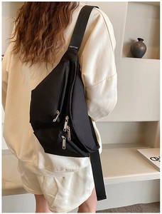 Detail view of black nylon crossbody bag with multi-zipper pockets and wide shoulder strap