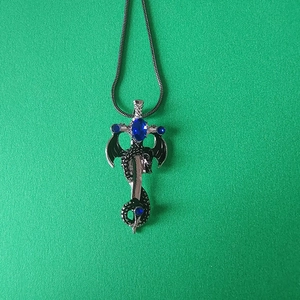 Gros plan détaillé d'un pendentif dragon et épée avec pierre bleue sur une chaîne serpent