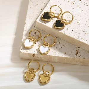 Three pairs of heart pendant hoop earrings in black, white, and gold on stone base