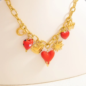 Détail du collier chaîne dorée avec cœurs en émail rouge et breloques célestes sur buste