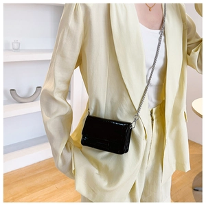 Detail of black crocodile texture small square bag with silver chain on model waist