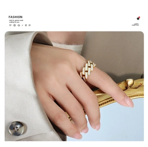 Detailed view of wide gold-plated steel ring with white enamel rectangular patterns