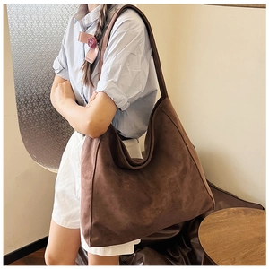 Close-up of brown suede tote bag showing soft texture and natural drape on model
