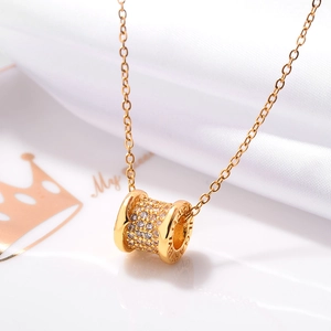 Macro shot of 18K rose gold cylinder pendant with pavé diamonds and side engraving