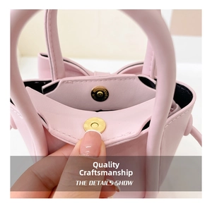 Detail showing the magnetic metal clasp and smooth pink leather texture of the bow crossbody bag