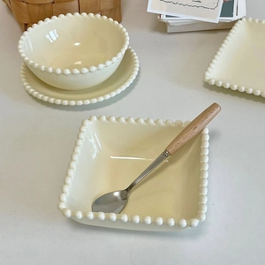 Cream ceramic bowl and dessert plate set with elegant beaded edges and wooden spoon