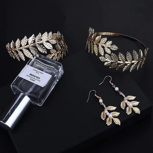 Detail view of golden leaf bridal hairpiece and pearl earrings set on dark backdrop