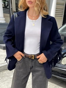 Street style view of a dark blue fringe jacket paired with grey jeans and a leather belt