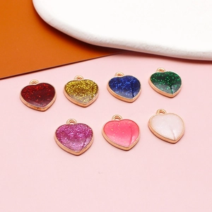 Macro shot of seven heart-shaped alloy charms with colorful glitter enamel and gold plating