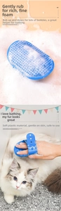 Detail of blue pet bath brush showing soft silicone bristles and usage on a white long-haired cat