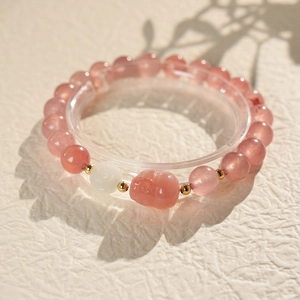 Macro detail of strawberry crystal beads with pink Pixiu charm and gold accents