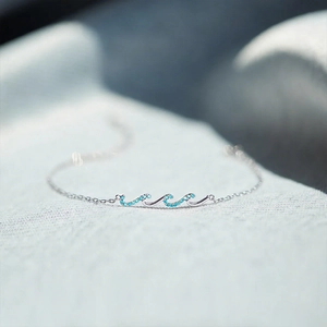 Vue macro d'un bracelet vague en argent serti de pierres bleues sur fond de tissu doux