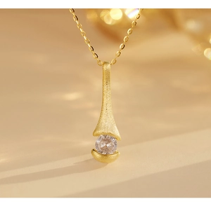 Macro detail of brushed gold pendant with clear round zircon on 925 silver necklace