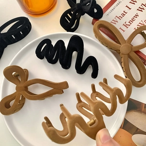 Barrettes à cheveux floquées élégantes en noir et caramel sur un plateau en céramique